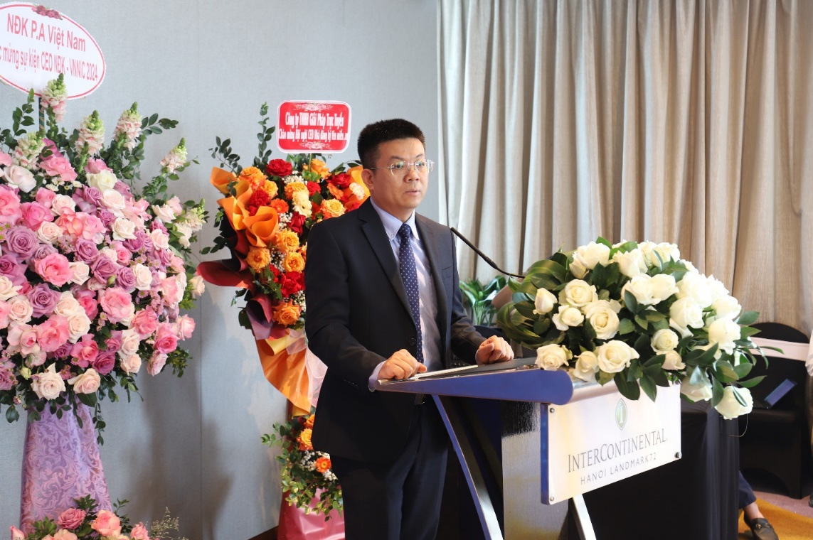 A person standing at a podium with flowers

Description automatically generated